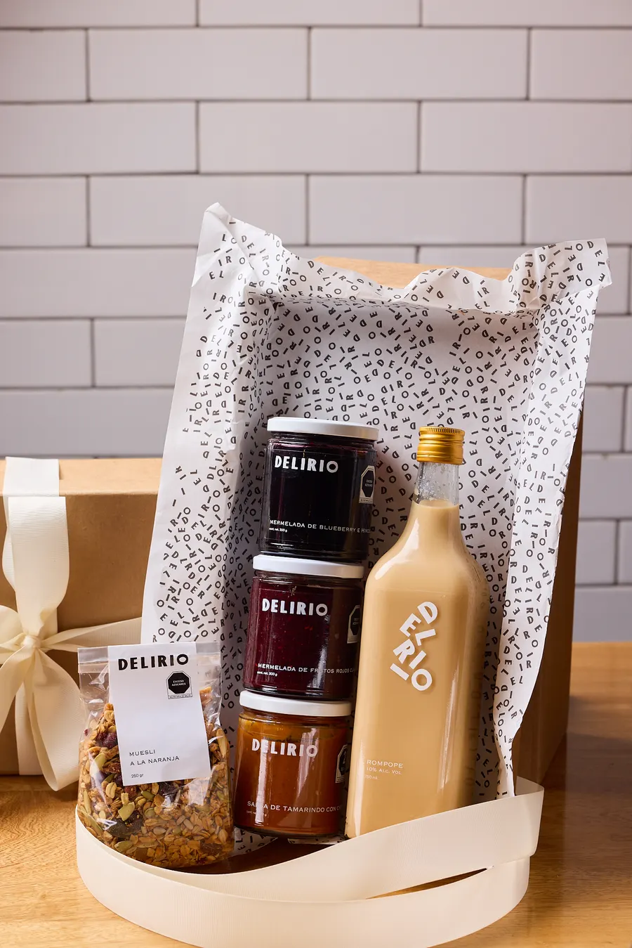 Canasta de regalo Delirio con frascos de mermelada, botella de crema, granola y bolsa de papel con patrón de la marca