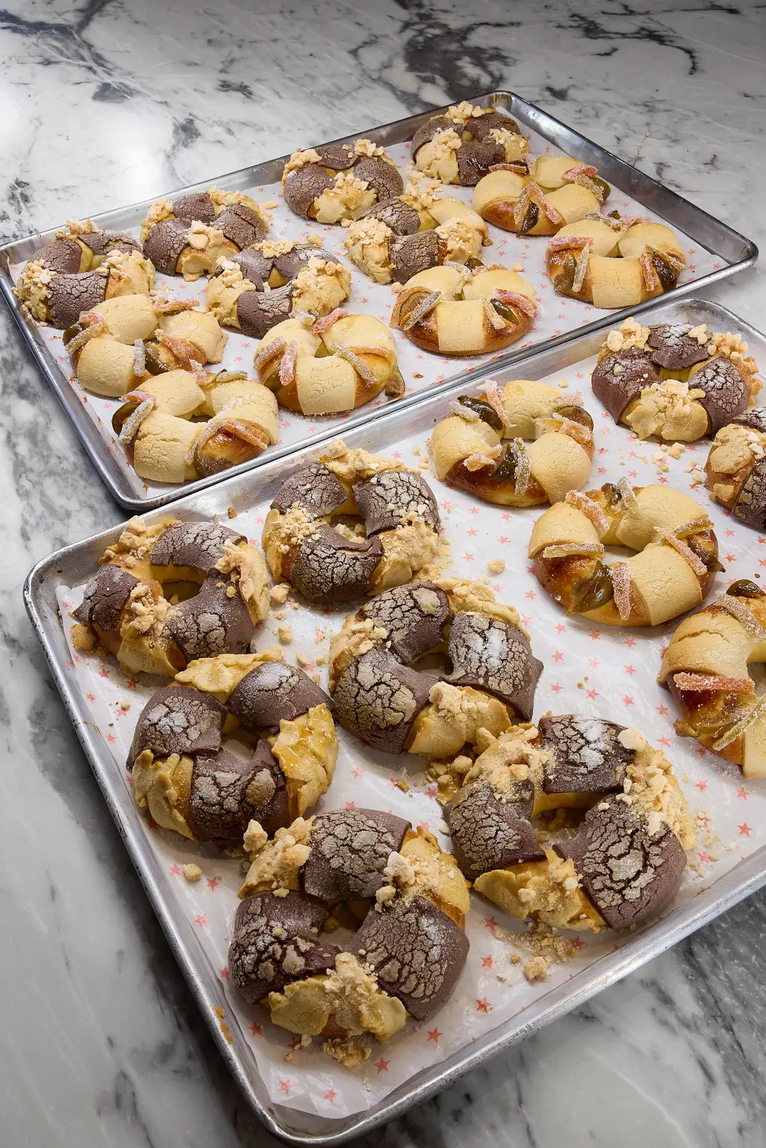 Charolas de horno con roscas de Reyes de chocolate y vainilla recién hechas, sobre una plancha de mármol