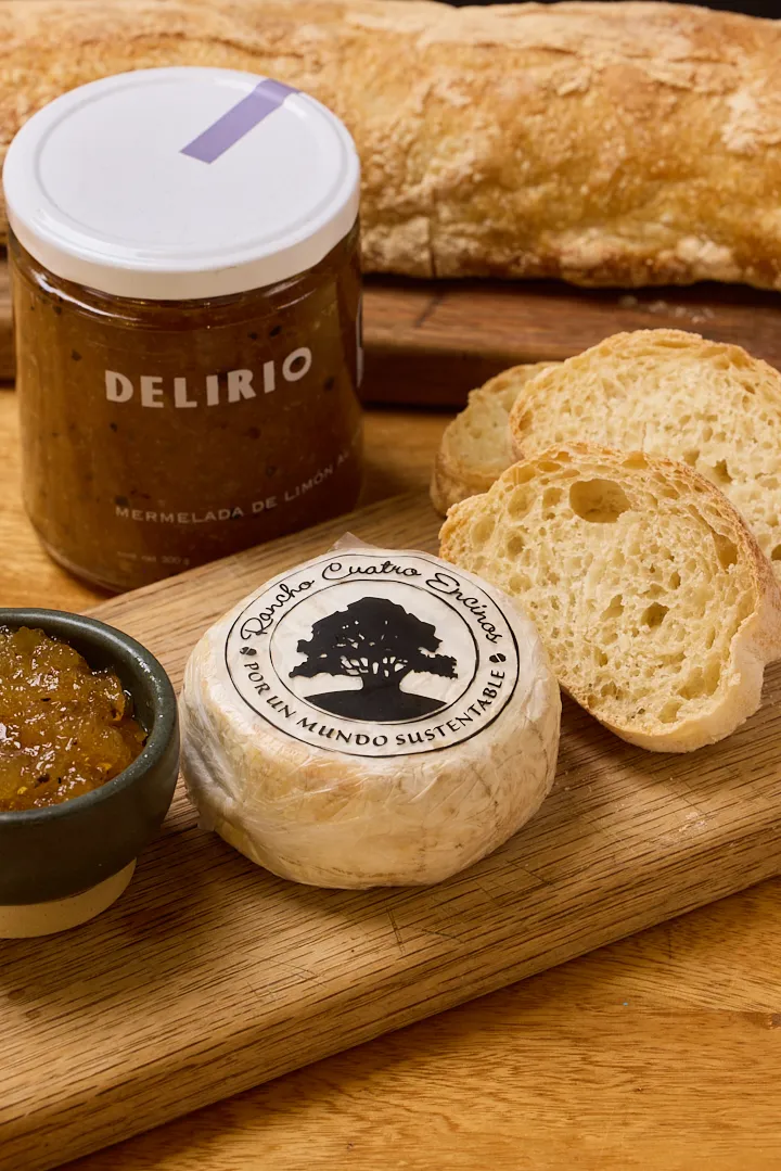Queso camembert artesanal sobre tabla de madera con mermelada de limón Delirio, pan y un cuenco pequeño