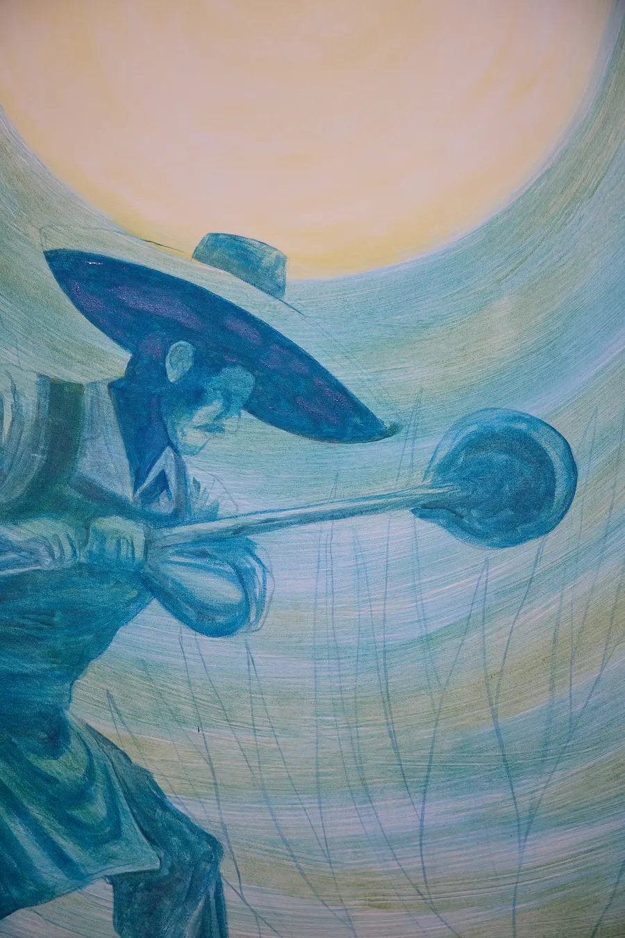 Detalle del mural terminado: un charro con sombrero sosteniendo un cazo, pintado en tonos azules sobre un sol amarillo