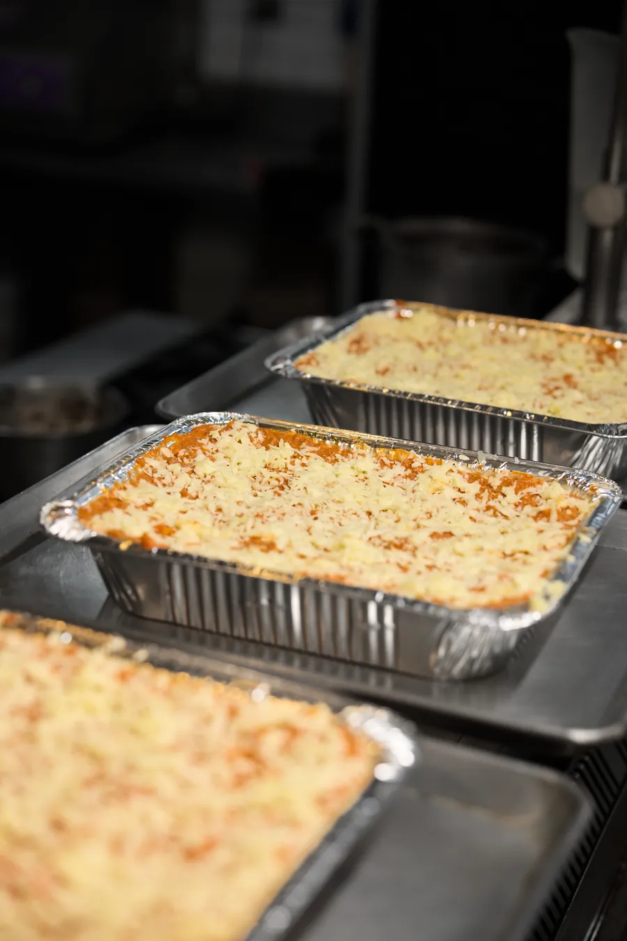 Charolas de lasaña recién gratinada sobre la plancha de la cocina, listas para fotografiar