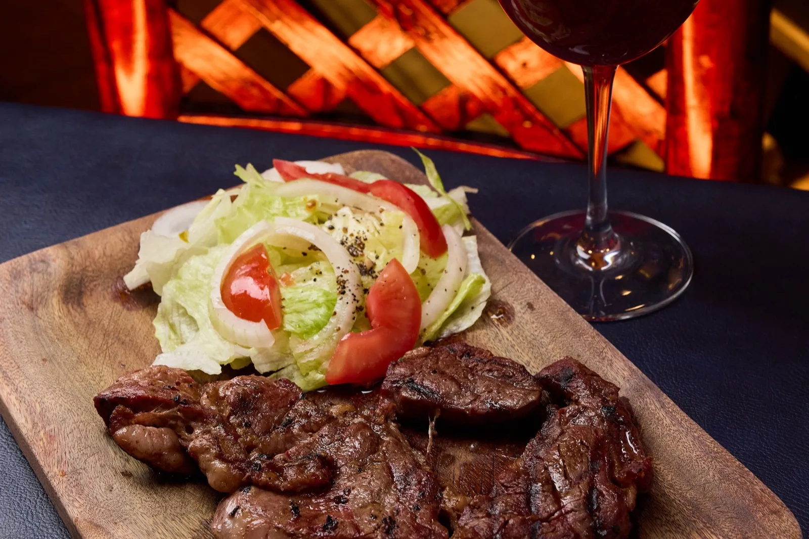 Corte a la parrilla en tabla, con su copa de vino, en El Peñar de los Pibes